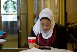 Fifi Youssef looks at her iPhone while seated in a Starbucks on Dec. 16 in New York; she is now suing the photographer and AP over their distribution of the photo. (Mark Lennihan/Associated Press)